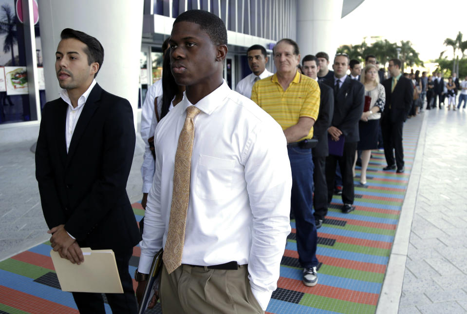 FILE - In this Wednesday, Oct. 23, 2013 file photo, Luis Mendez, 23, left, and Maurice Mike, 23, wait in line at a job fair held by the Miami Marlins, at Marlins Park in Miami. The labor Department issues the December jobs report, the last one for 2103, on January 10. 2014. (AP Photo/Lynne Sladky, FIle)