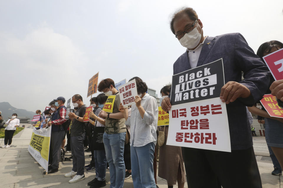 South Korean protesters take a moment of silence during a protest over the death of George Floyd, a black man who died after being restrained by Minneapolis police officers on May 25, near the U.S. embassy in Seoul, South Korea, Friday, June 5, 2020. The signs read "The U.S. government should stop oppression and there is no peace without justice." (AP Photo/Ahn Young-joon)