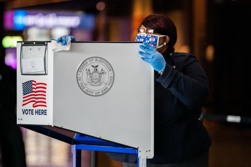 An election official sanitizes a privacy booth at a polling center in the Brooklyn Museum, November 3, 2020.