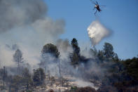 A helicopter drops water on the Oak Fire burning in Mariposa County, Calif., on Saturday, July 23, 2022. (AP Photo/Noah Berger)