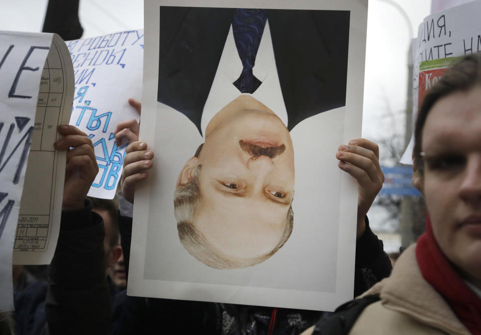 FILE - In this Wednesday, March 15, 2017 file photo, a protestor holds an overturned portrait of President Alexander Lukashenko during a rally in Minsk, Belarus. Belarus was shaken by months of protests sparked by the 2020 reelection of Lukashenko, which were widely seen as rigged. (AP Photo/Sergei Grits, File)