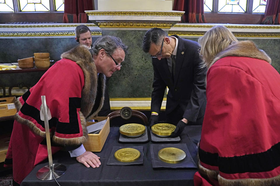 Coins are assessed during the "Trial of the Pyx,'' a ceremony that dates to the 12th Century in which coins are weighed in order to make certain they are up to standard, at the Goldsmiths' Hall in London, Tuesday, Feb. 7, 2023. A jury sat solemnly in a gilded hall in central London on Tuesday, presided over by a bewigged representative of the crown in flowing black robes, but there were no criminals in the dock. (AP Photo/Kin Cheung)