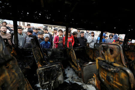 FILE PHOTO: People look at a burned vehicle at the site of car bomb attack in a busy square at Baghdad's sprawling Sadr City district, in Iraq January 2, 2017. REUTERS/Ahmed Saad/File Photo