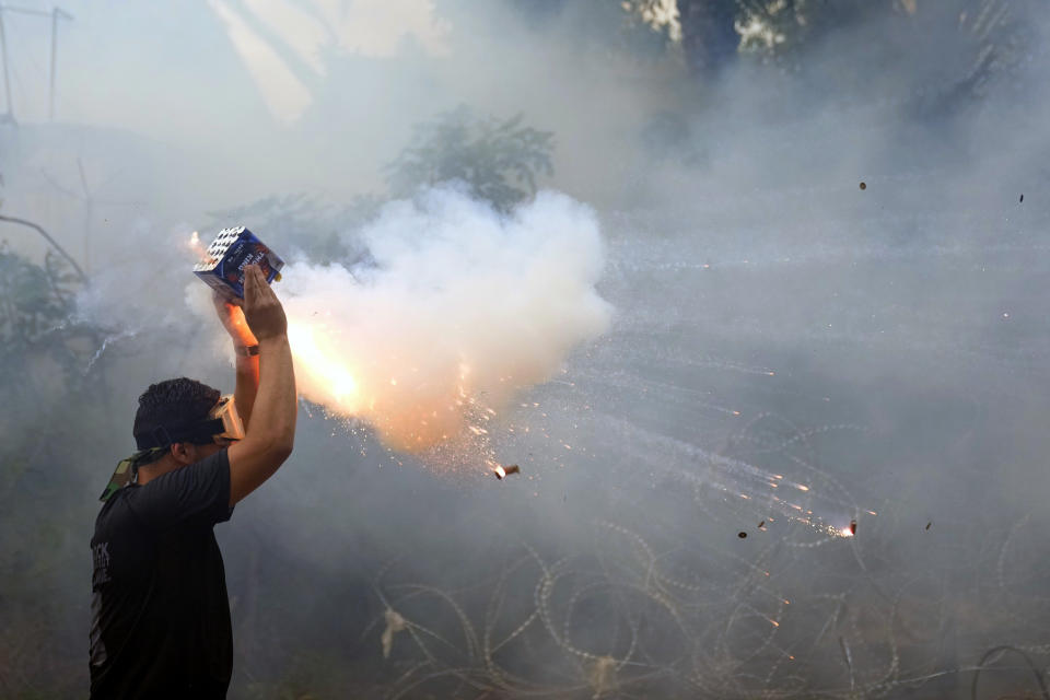 A protester launches fireworks at riot police during a demonstration, in solidarity with the Palestinian people in Gaza, near the U.S. embassy in Aukar, a northern suburb of Beirut, Lebanon, Wednesday, Oct. 18, 2023. Hundreds of angry protesters are clashing with Lebanese security forces in the Lebanese suburb Aukar near the United States Embassy. (AP Photo/Bilal Hussein)