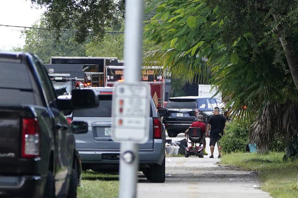 Local residents watch as fire and rescue personnel work in the area where a medical rescue helicopter crashed, Monday, Aug. 28, 2023, in Pompano Beach, Fla. (AP Photo/Marta Lavandier)