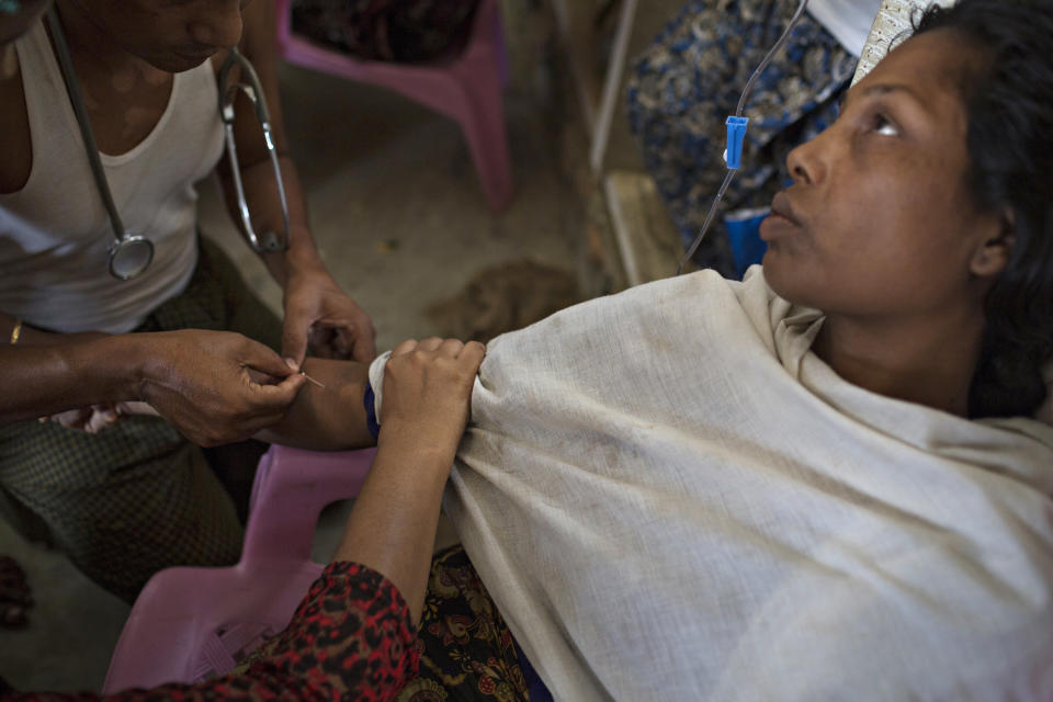 SITTWE, BURMA - MAY 07: A woman who complained of a high fever and stomach ache received an IV at a makeshift pharmecy and clinic in the Thet Kae Pyin refugee camp on May 7, 2014 in Sittwe, Burma. 150,000 Rohingya IDP (internally displaced people) are currently imprisoned in refugee camps outside of Sittwe in Rakhine State in Western Myanmar. Medecins Sans Frontieres (MSF), the primary supplier of medical care within the camps, was banned in March by the Myanmar government. Follow up attacks by Buddhist mobs on the homes of aid workers in Sittwe put an end to NGO operations in the camps. Though some NGOs are beginning to resume work, MSF remains banned, and little to no healthcare is being provided to most Rohingya IDPs. One Rohingya doctor is servicing 150,000 refugees with limited medication. Several Rakhine volunteer doctors sporadically enter the camps for two hours a day. Births are the most complicated procedures successfully carried out in the camps, and requests to visit Yangon or Sittwe hospitals for life threatening situations require lengthy applications and are routinely denied. Malnutrition and diarrhea are the most widespread issues, but more serious diseases like tuberculosis are going untreated and could lead to the rise of drug resistant tuberculosis (DR-TB). (Photo by Andre Malerba/Getty Images)