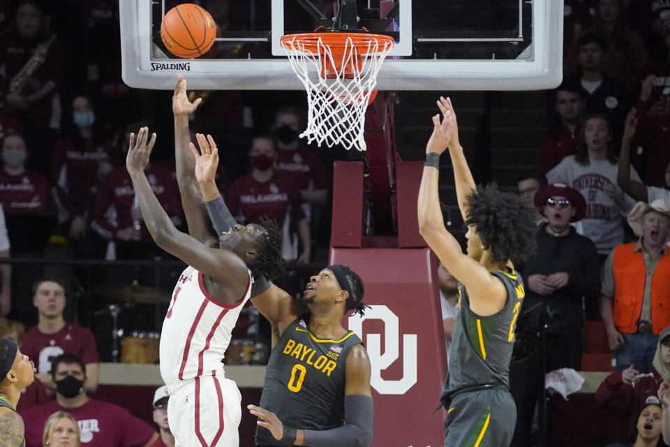 Oklahoma forward Akol Mawein, left, shoots in front of Baylor forward Flo Thamba (0) and guard Kendall Brown, right, in the first half of an NCAA college basketball game Saturday, Jan. 22, 2022, in Norman, Okla. (AP Photo/Sue Ogrocki)