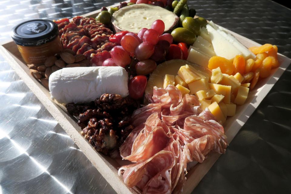 A charcuterie tray is displayed at the Long Branch Gourmet  Tuesday, November 8, 2022.  This plate features: Jasper Hill Farm Harbison, Manchego, Aged Gouda, Fresh Chevre, peach and apricot spread, Soppressata, wild boar sausage, fresh and dried fruit, olives, nuts and cornichons.