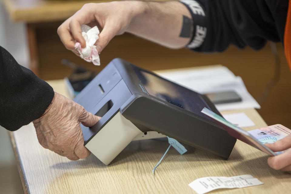 An Albanian woman's finger is scanned during parliamentary elections in capital Tirana, Albania on Sunday, April 25, 2021. Albanian voters have started casting ballots in parliamentary elections on Sunday amid the virus pandemic and a bitter political rivalry between the country's two largest political parties. (AP Photo/Visar Kryeziu)