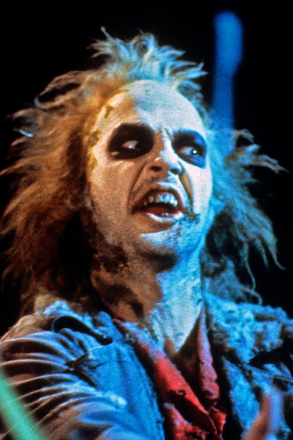 Michael Keaton as Beetlejuice, with tousled hair, face paint and grim expression, in a scene from the film 