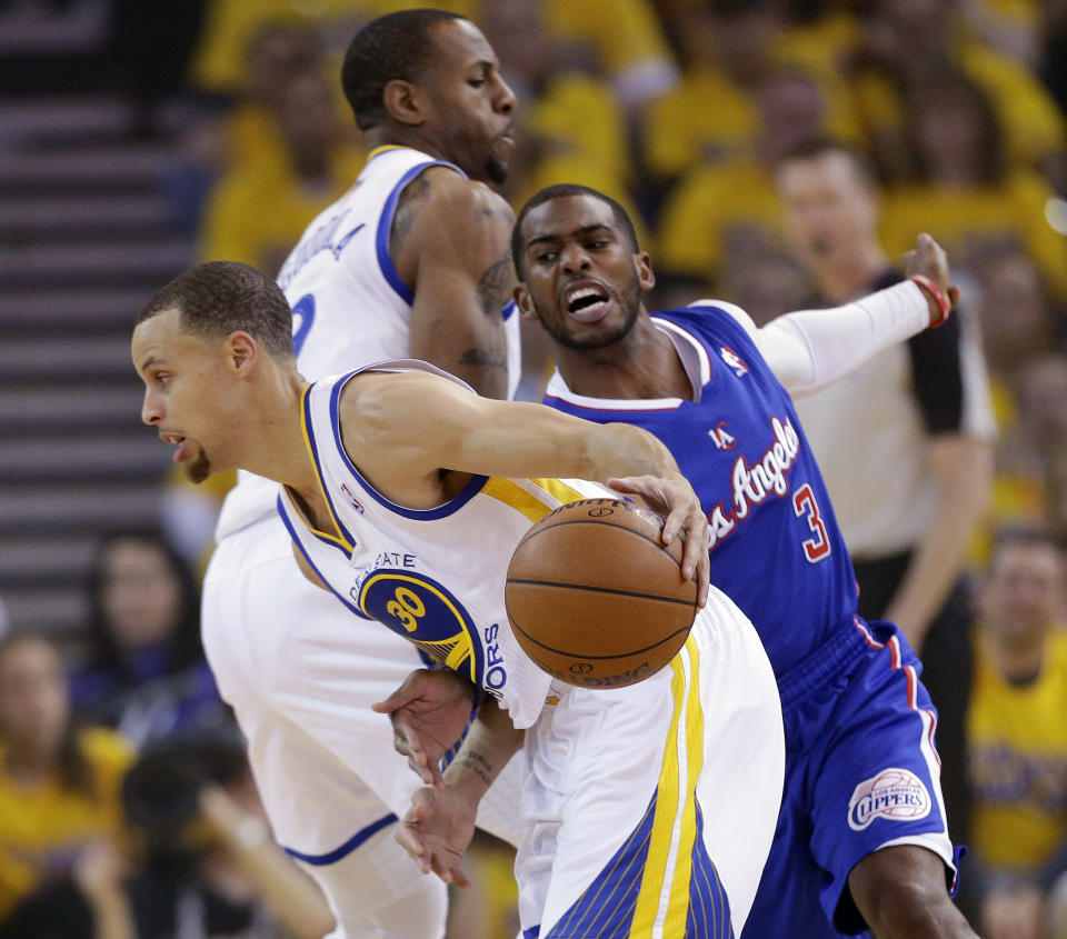 Golden State Warriors' Stephen Curry, front, dribbles around Los Angeles Clippers' Chris Paul (3) on a screen set by Andre Iguodala, left, during the first half in Game 3 of an opening-round NBA basketball playoff series, Thursday, April 24, 2014, in Oakland, Calif. (AP Photo/Marcio Jose Sanchez)