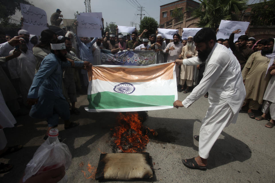 Pakistani people burn a representation of Indian flag during a demonstration to condemn derogatory references to Islam and the Prophet Muhammad recently made by Nupur Sharma, a spokesperson of the governing Indian Hindu nationalist party, Friday, June 10, 2022, in Peshawar, Pakistan. (AP Photo/Mohammad Sajjad)