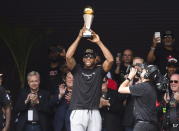 Toronto Raptors forward Kawhi Leonard hoists the MVP trophy next to teammates during the team's NBA basketball championship parade in Toronto, Monday, June 17, 2019. (Nathan Denette/The Canadian Press via AP)