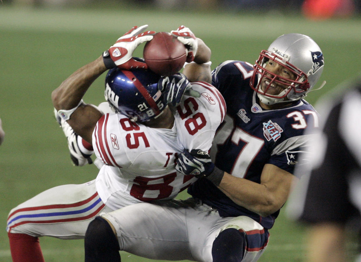 New York Giants receiver David Tyree (85) holds on by his fingertips to a 32-yard pass as New England Patriots safety Rodney Harrison (37) pulls him down after the catch during the fourth quarter of the Super Bowl football game Sunday, Feb. 3, 2008 in Glendale, Ariz. Somehow, with time running out and the ball pinned to his helmet, Tyree held on tight with both hands Sunday. Years from now, New York Giants fans will still wonder how he did it. The Giants won 17-14. (AP Photo/Elaine Thompson)