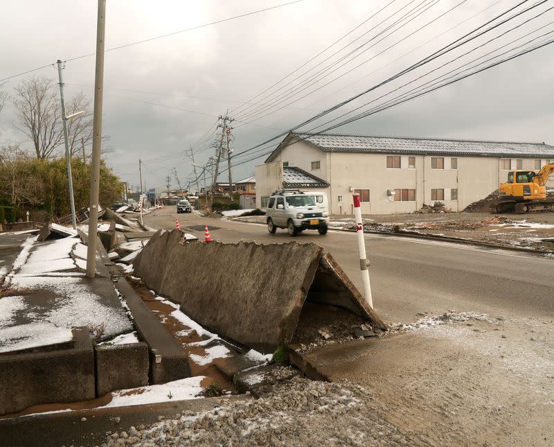 A car drives near a sidewalk damaged by the January 1 earthquake in Nishiaraya
