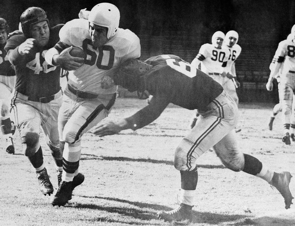 Otto Graham (60), Cleveland quarterback who led the Browns to a 34-24 victory over the Chicago Cardinals is brought down after a 7-yard gain by Bob Dove (left) and Bill Svoboda in the second quarter of game in Cleveland on Oct. 15, 1950. (AP Photo/Julian C. Wilson)