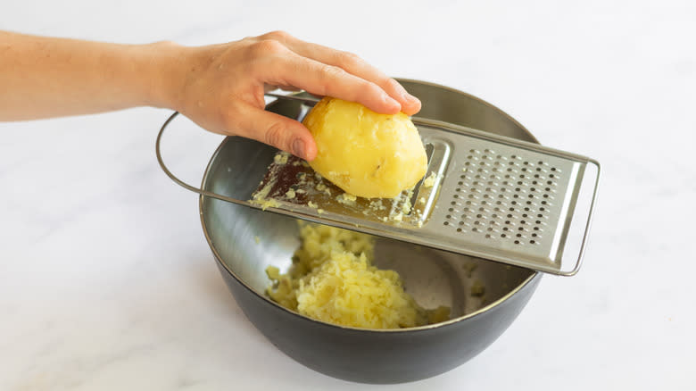 grating potatoes into bowl