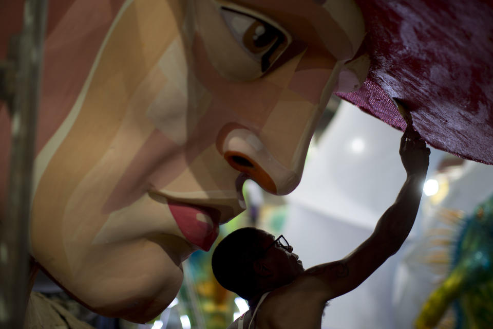 In this photo taken Tuesday, Jan. 22, 2013, a man paints a Carnival float sculpture at the Grande Rio Samba school in Rio de Janeiro, Brazil. Yet it's from warehouses like this one that Rio's over-the-top glitz-and-glam Carnival parades emerge, as they will Monday night for the final round of a two-day performance. The internationally renowned competition between 12 elite samba groups dazzles more than a billion spectators in person and on TV for two days, but it takes nearly a year and hundreds of workers, many of them volunteers, to pull each one together. (AP Photo/Felipe Dana)