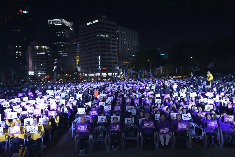 Familiares de personas que murieron en estampida y simpatizantes muestran carteles con la frase "Descubran la verdad" durante una ceremonia para conmemorar el primer aniversario de la catástrofe que cobró la vida de 159 personas, en la Plaza Seúl, en Seúl, Corea del Sur, el domingo 29 de octubre de 2023. (AP Foto/Ahn Young-joon)