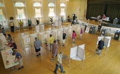 A polling place in a public building with booths and voters.