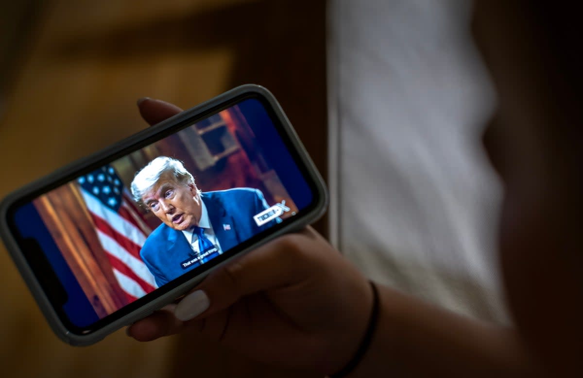 A viewer watches former President and Republican presidential candidate Donald Trump's interview by Tucker Carlson on the platform 'X' on their phone in Miami, Florida, USA (EPA)