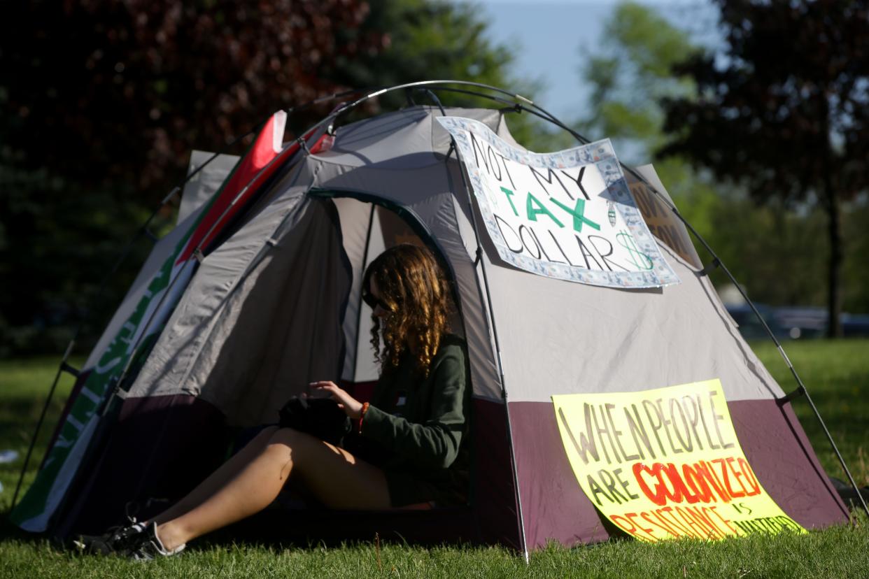 Vivian Shields rests in a tent decorated with signs reading “Not my Tax Dollar$” and “When people are colonized resistance is justified” Friday, May 3, 2024 at the City High school protest over the Israel-Hamas war in Iowa City, Iowa.