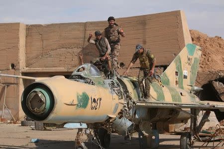 FILE PHOTO: Syrian Democratic Forces (SDF) fighters gesture while posing on a damaged airplane inside Tabqa military airport after taking control of it from Islamic State fighters, west of Raqqa city, Syria April 9, 2017. REUTERS/Rodi Said