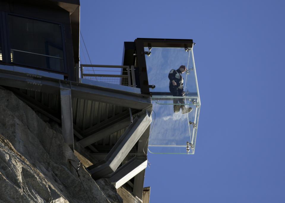 A man stands in the 'Step into the Void' installation at the Aiguille du Midi mountain peak above Chamonix, in the French Alps