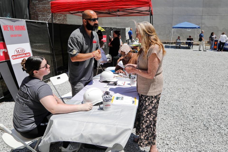 A woman speaks with representatives of MJD Excavating at a job fair hosted by D.F. Pray held at the former Keystone Building location on Union Street in New Bedford. Nineteen subcontractors were on hand looking for local workers.