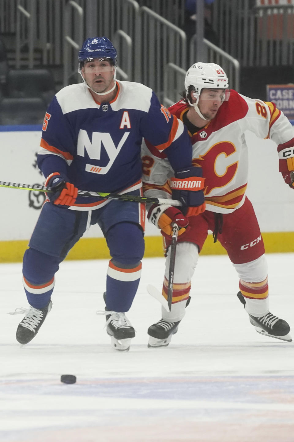 New York Islanders' Cal Clutterbuck, left, and Calgary Flames' Jakob Pelletier, right, chase a loose puck during the second period of an NHL hockey game, Saturday, Feb. 10, 2024, in New York. (AP Photo/Bebeto Matthews)