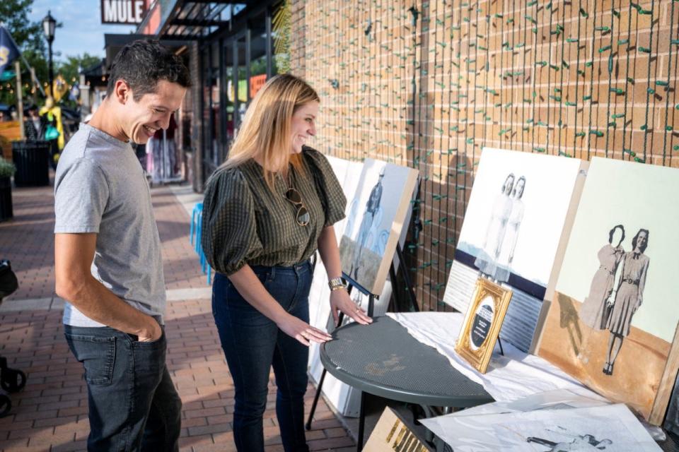Visual Artist Natalie Biggs and Customer Looking at Natalie & Eric Lyons Art at October 2022 VIBES event.