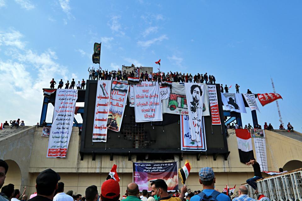 In this Oct. 30, 2019, photo, Iraqi anti-government protesters hang their demands and slogans while standing on a building near Tahrir Square, Baghdad, Iraq. An abandoned building in central Baghdad has emerged as the epicenter of anti-government protests in Iraq, with hundreds holed up inside. The Saddam Hussein-era building known as the “Turkish Restaurant” overlooks Tahrir Square, the Tigris River and the Green Zone, and protesters who took it over on Oct. 25 have sworn not to leave it. (AP Photo/Hadi Mizban)