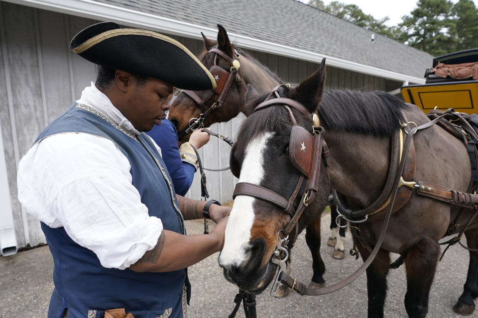 Colonial Williamsburg coachman Collin Ashe prepares his horse, Commodore, to pull a coach Thursday Feb. 24, 2022, in Williamsburg, Va. Colonial Williamsburg has begun to honor the coachmen by naming a new carriage after one of them. (AP Photo/Steve Helber)