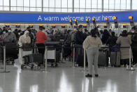 Passengers queue to check in at Heathrow Airport in London, Monday, Nov. 29, 2021. The new potentially more contagious omicron variant of the coronavirus popped up in more European countries on Saturday, just days after being identified in South Africa, leaving governments around the world scrambling to stop the spread. In Britain, Prime Minister Boris Johnson said mask-wearing in shops and on public transport will be required, starting Tuesday. (AP Photo/Frank Augstein)