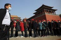 A man wearing a face mask to help curb the spread of the coronavirus walks by masked tourists lining up to enter Forbidden City in Beijing, Sunday, Oct. 25, 2020. With the outbreak of COVID-19 largely under control within China's borders, the routines of normal daily life have begun to return for its citizens. (AP Photo/Andy Wong)