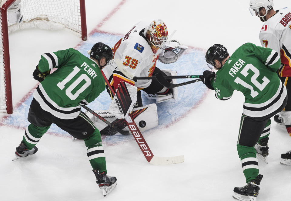 Calgary Flames goalie Cam Talbot (39) makes the save on Dallas Stars' Corey Perry (10) as Stars' Radek Faksa (12) tries to get the rebound during the second period of a first round NHL Stanley Cup playoff hockey series in Edmonton, Alberta, on Thursday, Aug. 13, 2020. (Jason Franson/The Canadian Press via AP)