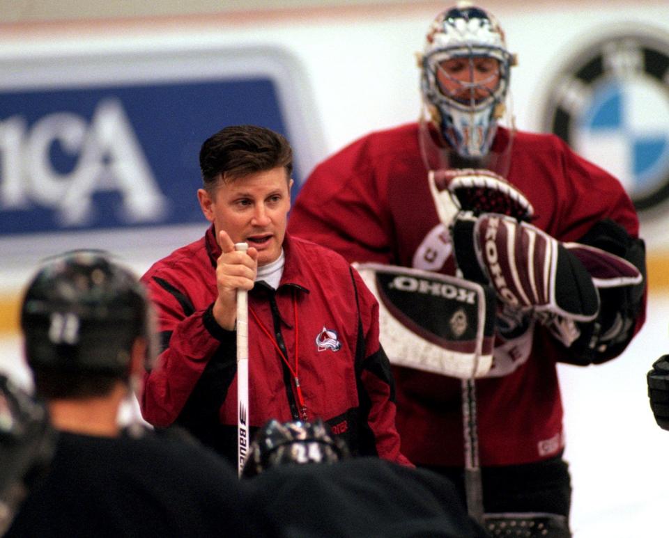 Colorado Avalanche coach Marc Crawford talks with his players, as goalie Patrick Roy stands in the background, during practice at Joe Louis Arena, May 21, 1997, ahead of Game 4 of the Western Conference finals against the Detroit Red Wings.
