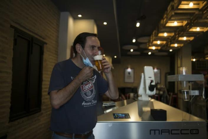 Albero Marinez, owner of the 'La Gitana Loca' bar says he bought the robot before the epidemic took hold hoping to boost sales (AFP Photo/CRISTINA QUICLER)