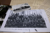 A photograph of a school building and a photocopy of a class picture on top of the report cards of Fumie Sato's first to sixth grades from the elementary school in Manchuria, China, are seen Friday, Aug. 7, 2020, at her home in Yokohama, Japan. Hours after Sato heard Emperor Hirohito's Aug. 15 radio speech declaring Japan's defeat at her school ground in Manchuria, China, she had to be prepared for honorable suicide with her family, though her father decided his family must live. Two years later she almost became an orphan when her little sister died of illness after their mother and little brother took an earlier boat back to Japan. (AP Photo/Kiichiro Sato)