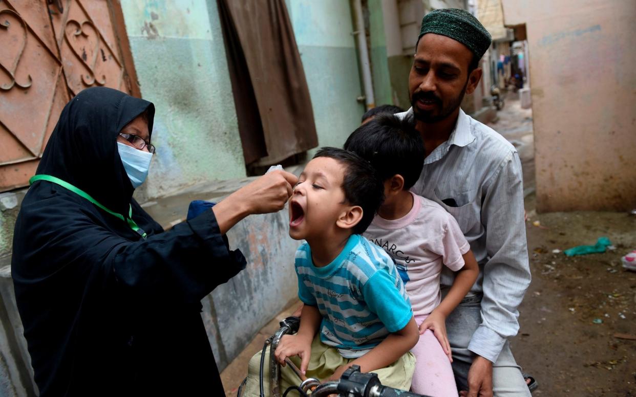 A health worker administers polio vaccine drops to a child during a polio vaccination door-to-door campaign in Pakistan's port city of Karachi  - RIZWAN TABASSUM /AFP