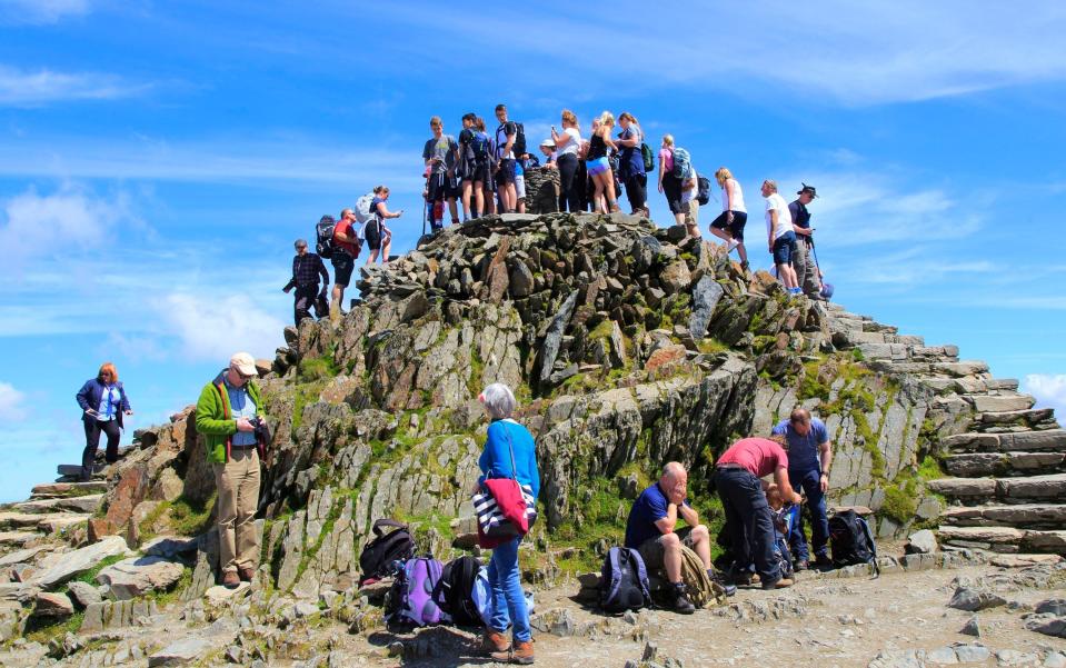 Walkers crowd onto the summit point of Snowdon