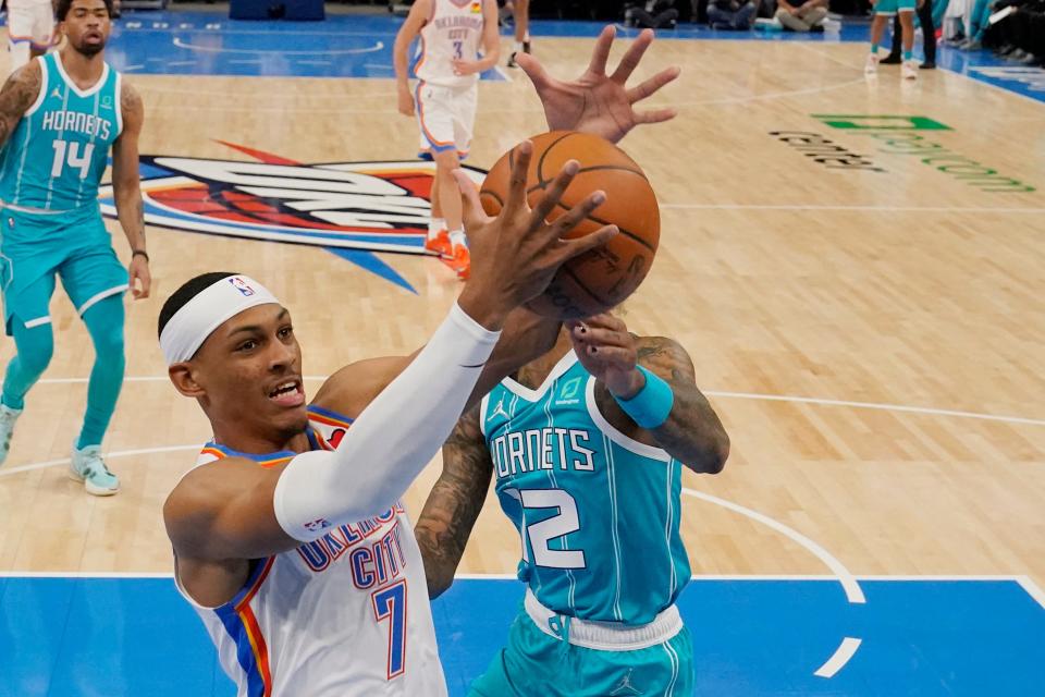 Oklahoma City Thunder forward Darius Bazley (7) grabs a rebound in front of Charlotte Hornets guard Kelly Oubre Jr. (12) in the first half of a preseason NBA basketball game, Monday, Oct. 4, 2021, in Oklahoma City. (AP Photo/Sue Ogrocki)