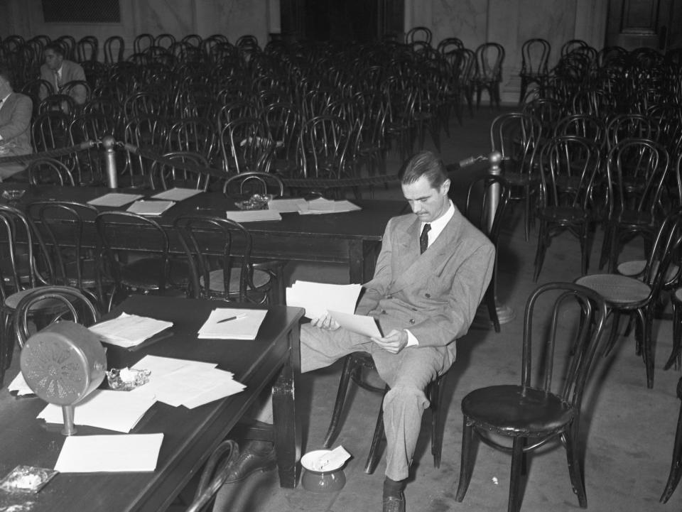 Howard Hughes is shown here seated alone in the normally jam-packed Senate caucus room.