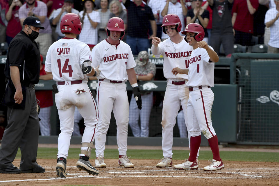 Arkansas batter Cullen Smith (14) is greeted by teammates Cayden Wallace (7), Matt Goodheart (10) and Robert Moore (1) after hitting a grand slam against North Carolina State in the second inning of an NCAA college baseball super regional game Friday, June 11, 2021, in Fayetteville, Ark. (AP Photo/Michael Woods)