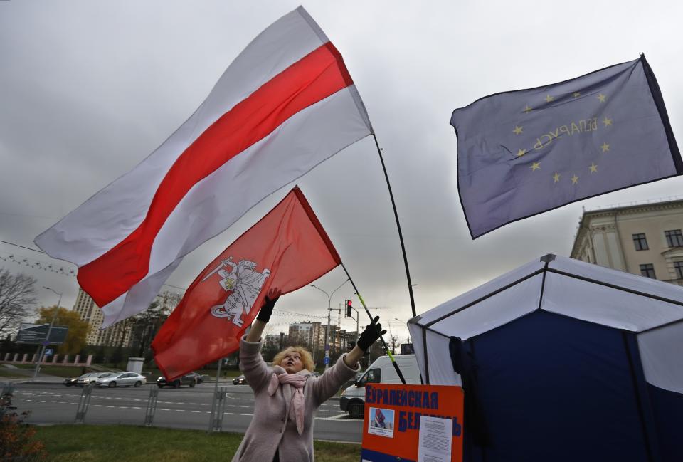 In this photo taken on Monday, Nov. 11, 2019, a woman sets an old Belarus' flag at an election tent in Minsk, Belarus, ahead of the parliamentary election to be held on Sunday. (AP Photo/Sergei Grits)