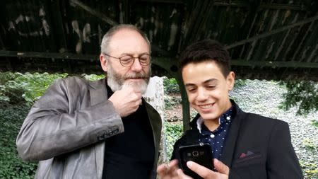 Games of Thrones star Liam Cunningham smiles together with his supporter Syrian migrant Hussam Alheraky as he made a surprise vist in Stuttgart, Germany, October 11, 2016. REUTERS/Reuters Tv