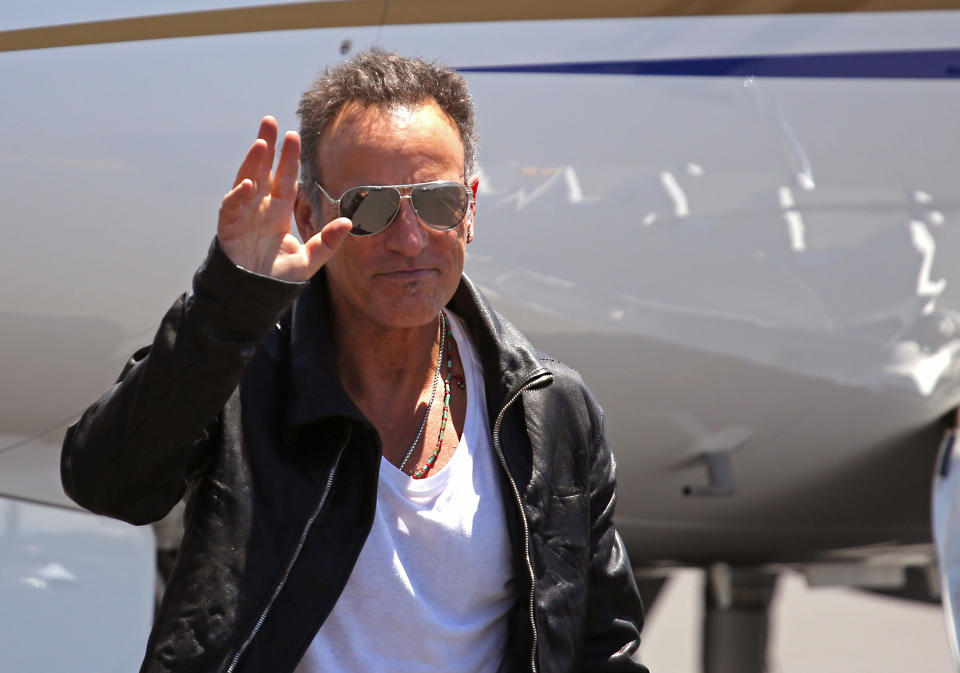 American performer Bruce Springsteen, waves as he arrives at the airport in Cape Town, South Africa, Friday, Jan. 24, 2014. Bruce Springsteen will begin his first South African tour on Sunday, Jan. 26, in Cape Town. (AP Photo/Schalk van Zuydam)