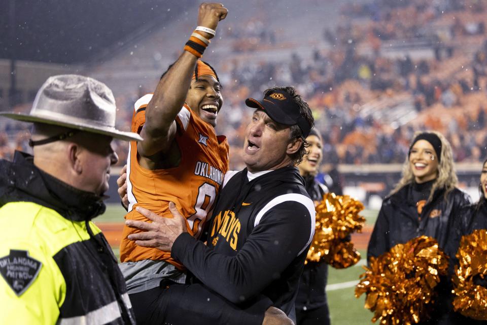 Oklahoma State wide receiver Brennan Presley (80) celebrates in the arms of Oklahoma State coach Mike Gundy arms after an NCAA college football game against BYU on Saturday, Nov. 25, 2023, in Stillwater, Okla. | Mitch Alcala, Associated Press