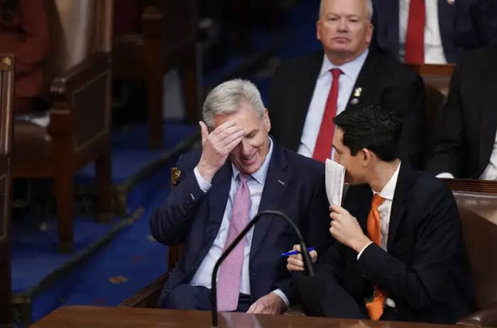 Rep. Kevin McCarthy doing a small grin with his face in his hands in the House chamber