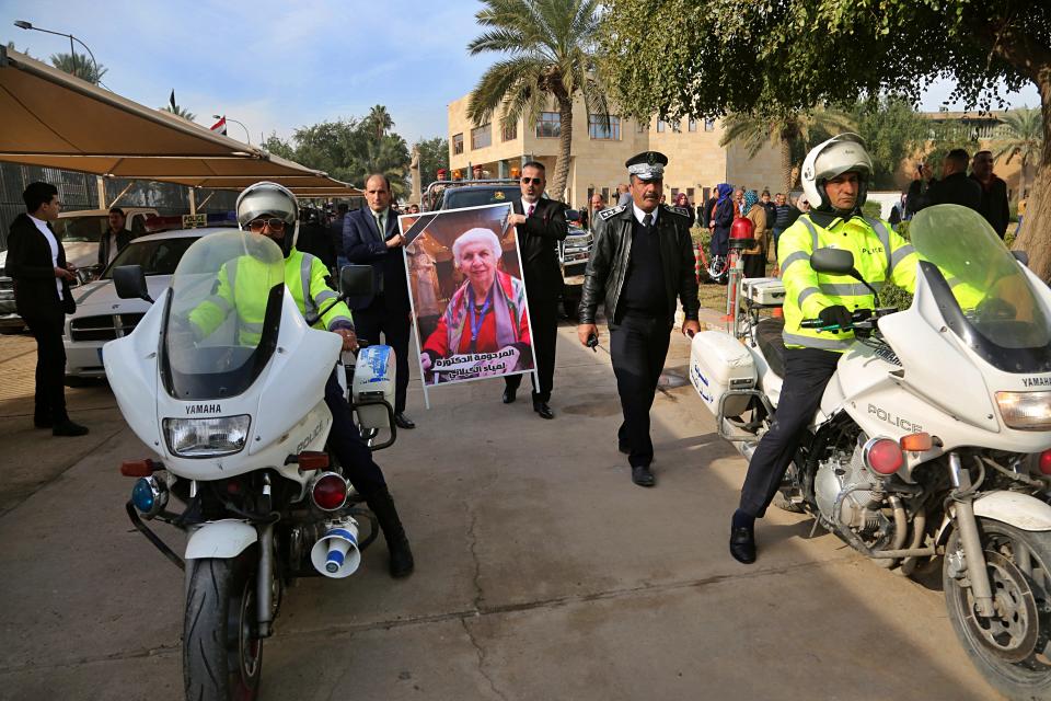 The flag-draped coffin of Iraqi archaeologist, Lamia al-Gailani, seen in the poster, is transported for burial during her funeral procession in the National Museum in Baghdad, Iraq, Monday, Jan. 21, 2019. Iraq is mourning the loss of a beloved archaeologist who helped rebuild her country's leading museum in the aftermath of the U.S. invasion in 2003. (AP Photo/Khalid Mohammed)